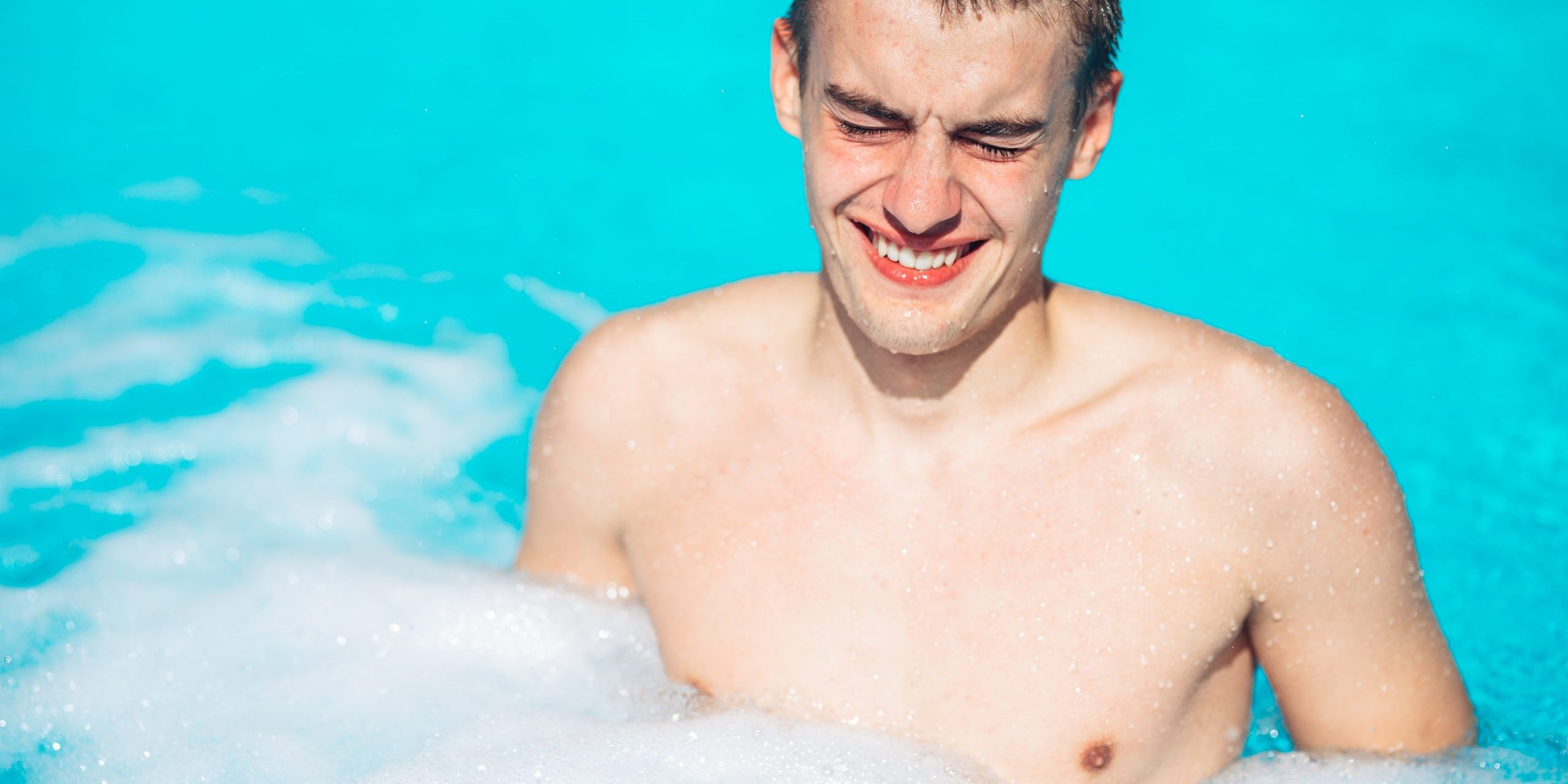 Young man rubbing eyes in swimming pool.Summer activity.Contact lens pollution, swimming in chlorine contaminated pool.Eyes burning in the pool.Allergy on chlorine chemical disinfection in water.